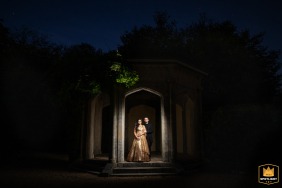 A couple poses for a nighttime portrait at Shendish Manor. The photo captures their wedding day, with the historic building illuminated in the background.